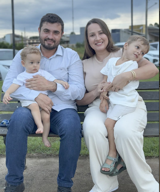 Ana, o marido Murilo e dois dos filhos sentados num banco de praça no fim da tarde